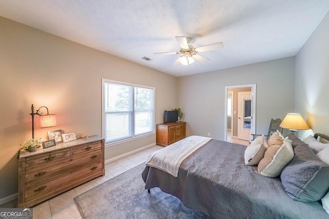 tiled bedroom featuring a textured ceiling, connected bathroom, and ceiling fan