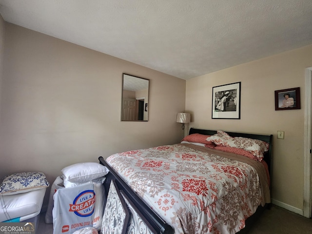 bedroom with a textured ceiling and dark colored carpet