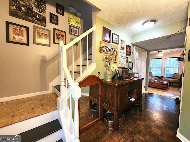 stairs featuring ceiling fan, parquet flooring, and a textured ceiling