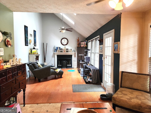 living room with vaulted ceiling, hardwood / wood-style floors, a textured ceiling, and ceiling fan