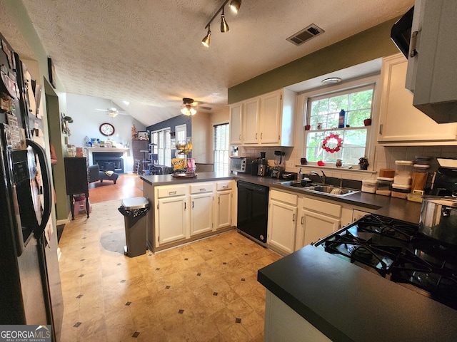 kitchen with sink, vaulted ceiling, black dishwasher, kitchen peninsula, and ceiling fan