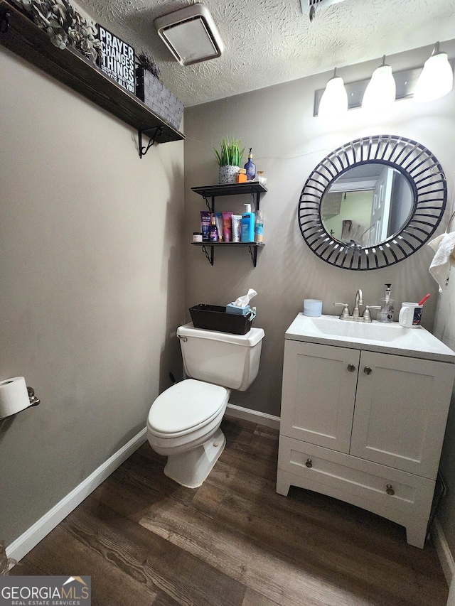 bathroom with vanity, toilet, hardwood / wood-style floors, and a textured ceiling