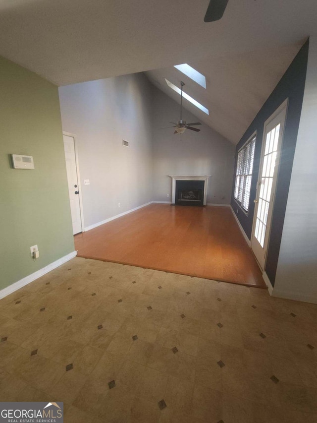 unfurnished living room with high vaulted ceiling, ceiling fan, and a skylight