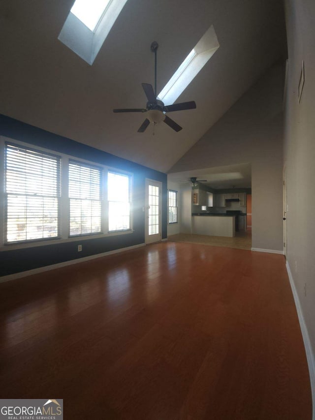 unfurnished living room with high vaulted ceiling, hardwood / wood-style floors, ceiling fan, and a skylight