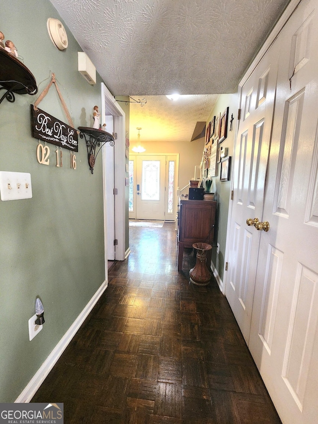 hallway featuring dark parquet flooring and a textured ceiling