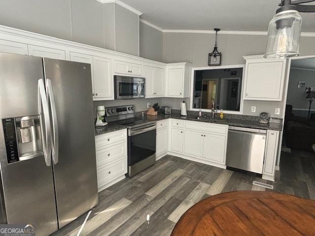 kitchen with pendant lighting, sink, white cabinets, ornamental molding, and stainless steel appliances