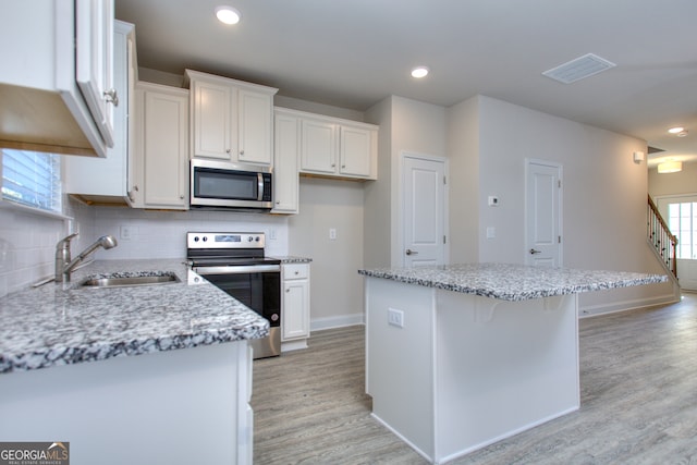 kitchen featuring appliances with stainless steel finishes, white cabinets, and a wealth of natural light