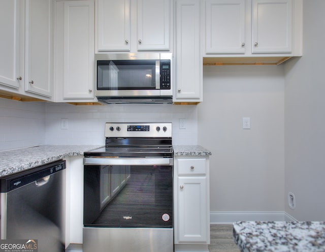 kitchen featuring light stone countertops, stainless steel appliances, and white cabinetry