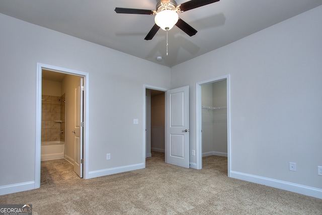 unfurnished bedroom with ceiling fan, light carpet, ensuite bathroom, and a walk in closet