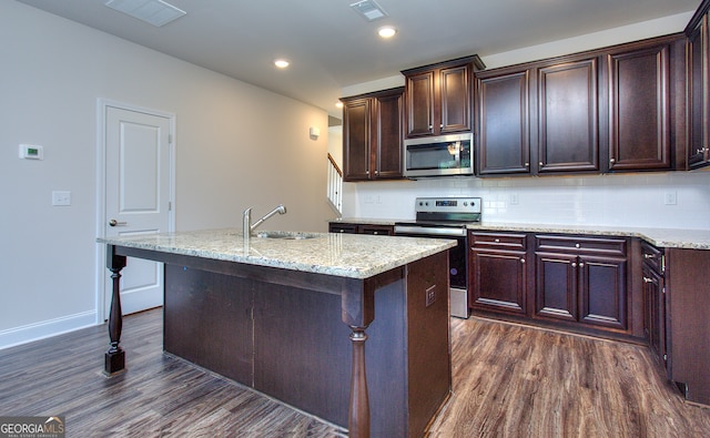 kitchen featuring an island with sink, sink, stainless steel appliances, a kitchen breakfast bar, and dark hardwood / wood-style flooring