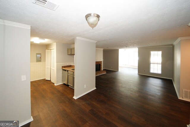 interior space with a textured ceiling, electric panel, dark hardwood / wood-style floors, a brick fireplace, and ornamental molding