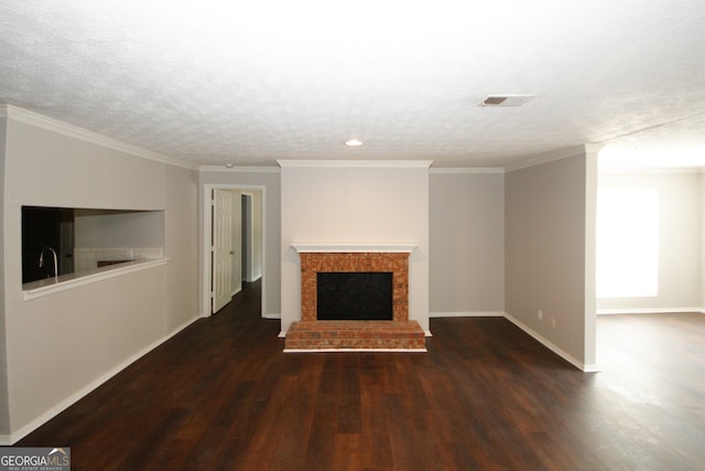 unfurnished living room with a brick fireplace, a textured ceiling, crown molding, and dark hardwood / wood-style flooring