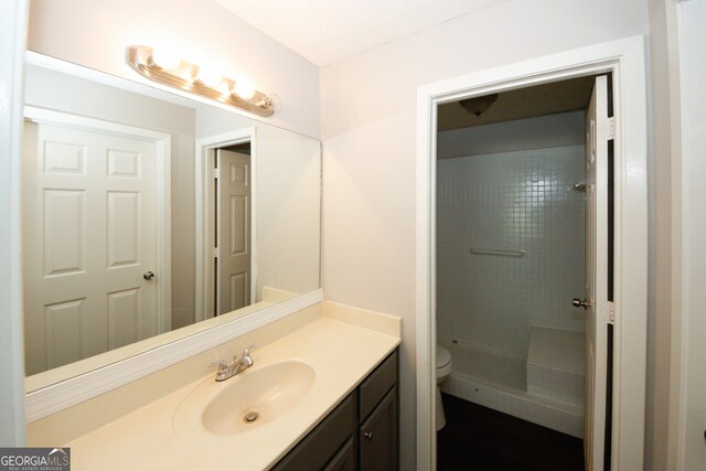 bathroom featuring tiled shower, vanity, and toilet