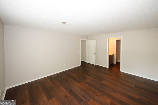 spare room featuring a textured ceiling and dark wood-type flooring