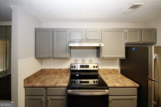 kitchen with gray cabinets, decorative backsplash, a textured ceiling, and stainless steel appliances