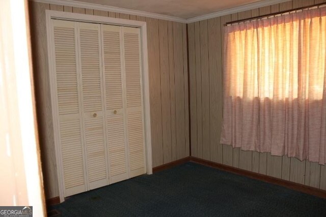 unfurnished bedroom featuring ornamental molding, a closet, and dark carpet