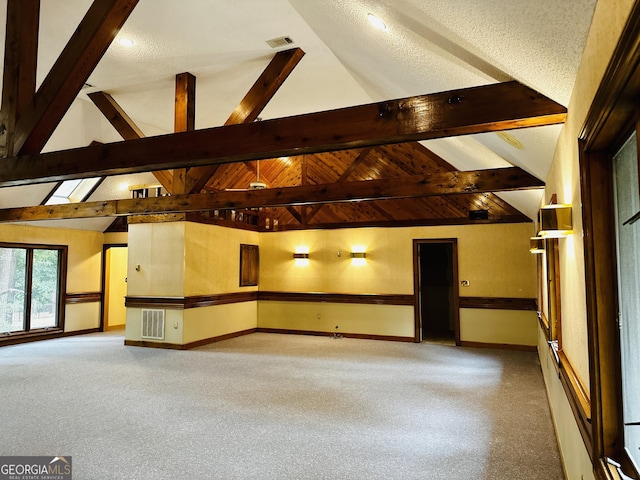 carpeted spare room with lofted ceiling with beams and a textured ceiling