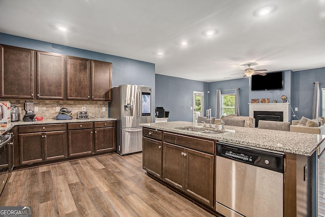 kitchen featuring dark brown cabinetry, a center island with sink, light wood-type flooring, and appliances with stainless steel finishes