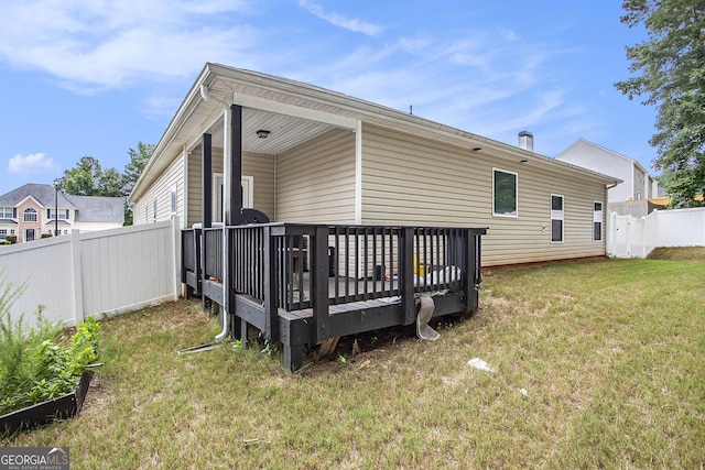 rear view of property with a deck and a lawn