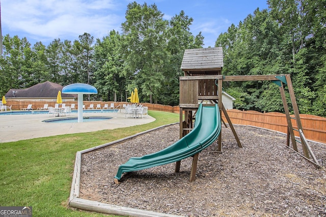 view of playground featuring a yard, a patio area, and a community pool