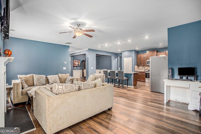 living room featuring ceiling fan and dark hardwood / wood-style floors