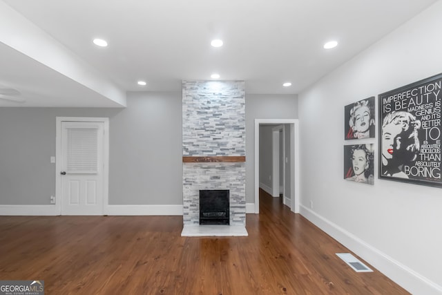 unfurnished living room featuring a stone fireplace, recessed lighting, wood finished floors, visible vents, and baseboards