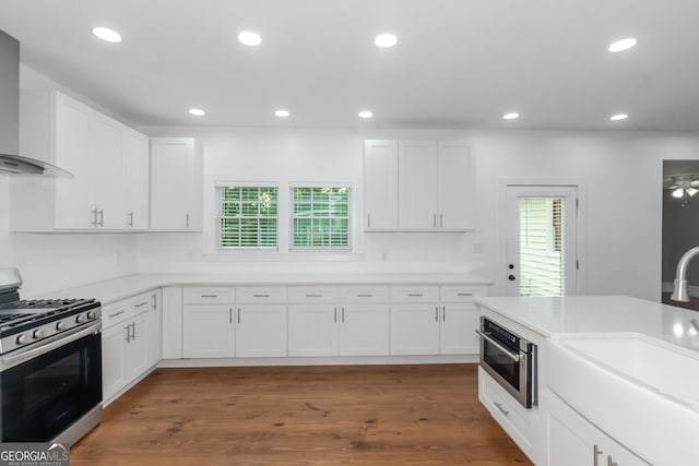 kitchen with wall chimney exhaust hood, appliances with stainless steel finishes, and white cabinetry