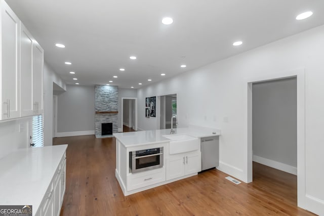 kitchen with a peninsula, a sink, visible vents, white cabinetry, and appliances with stainless steel finishes