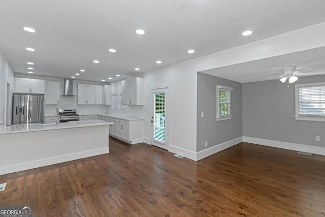 kitchen featuring dark wood finished floors, stainless steel appliances, light countertops, visible vents, and wall chimney range hood