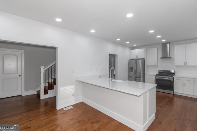 kitchen with dark wood-style floors, appliances with stainless steel finishes, a sink, a peninsula, and wall chimney exhaust hood