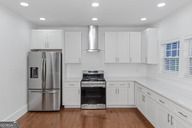 kitchen featuring appliances with stainless steel finishes, light countertops, white cabinets, and wall chimney range hood