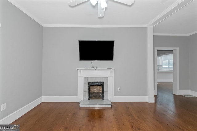 unfurnished living room featuring ornamental molding, a tile fireplace, baseboards, and wood finished floors