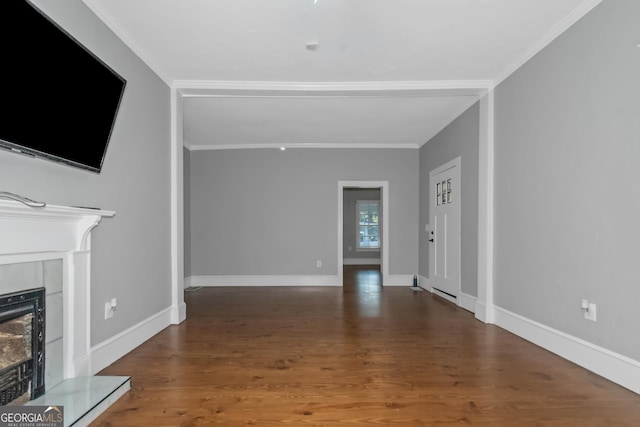 unfurnished living room featuring crown molding, baseboards, a fireplace with raised hearth, and wood finished floors