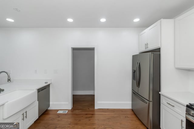 kitchen featuring stainless steel appliances, visible vents, a sink, and white cabinetry