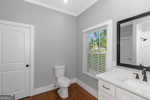 bathroom featuring toilet, wood finished floors, vanity, baseboards, and crown molding