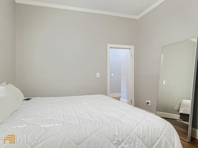 bedroom featuring baseboards, crown molding, and wood finished floors