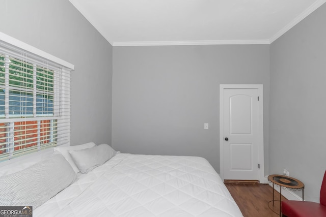 bedroom with ornamental molding and wood finished floors