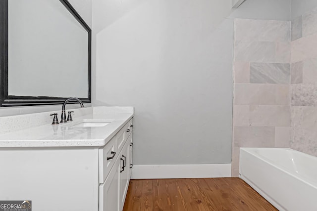 full bath with wood finished floors, vanity, and baseboards