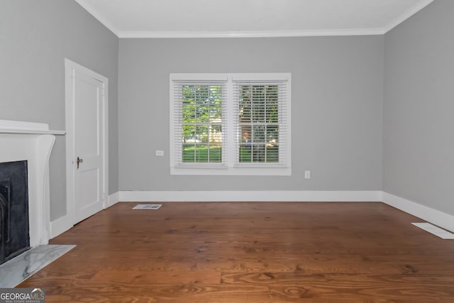 unfurnished living room featuring baseboards, visible vents, a fireplace with flush hearth, ornamental molding, and wood finished floors