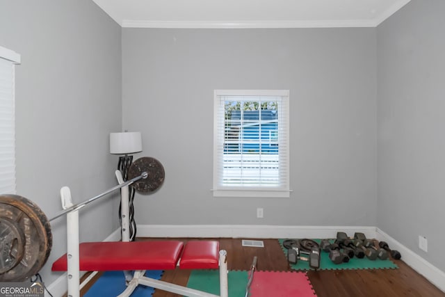 workout area with crown molding, visible vents, baseboards, and wood finished floors