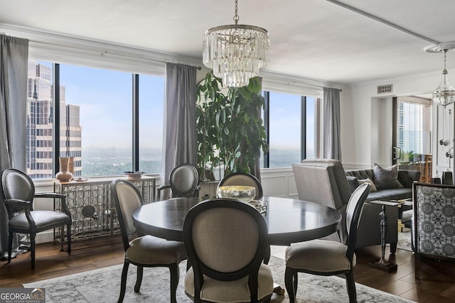 dining space with a water view, plenty of natural light, a notable chandelier, and wood finished floors