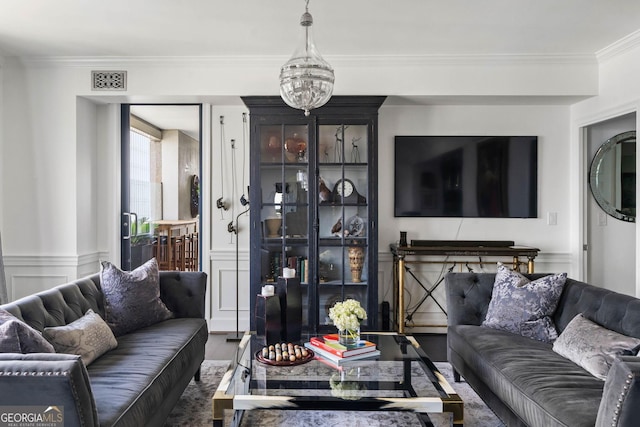 living area featuring crown molding, visible vents, wood finished floors, and wainscoting