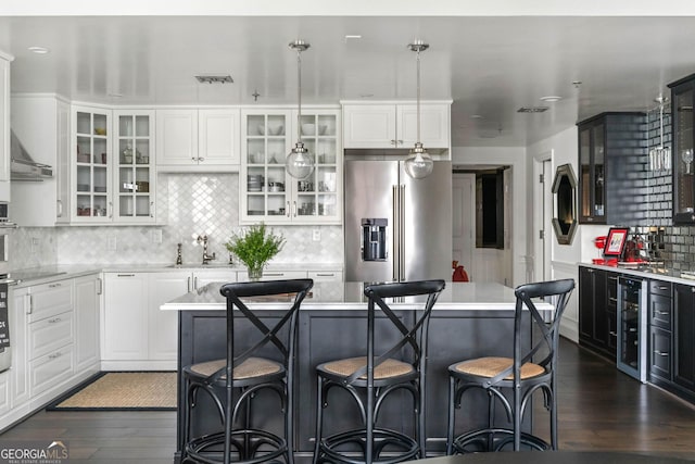 kitchen with a center island, pendant lighting, high end fridge, light countertops, and glass insert cabinets