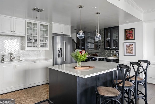 kitchen featuring a sink, white cabinetry, high end fridge, a center island, and glass insert cabinets