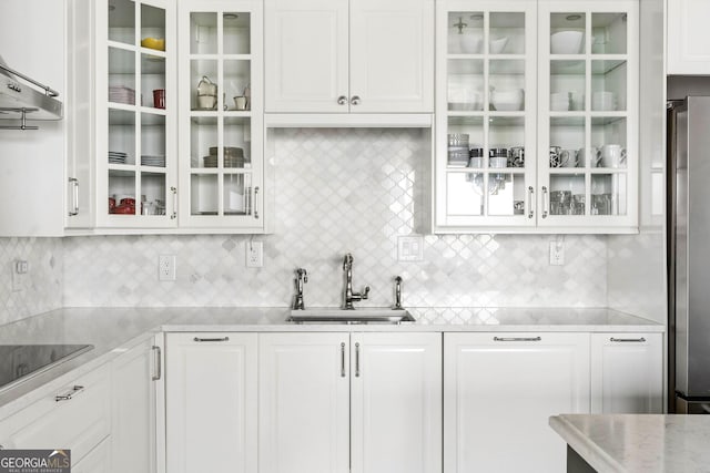 kitchen with glass insert cabinets, white cabinets, a sink, and freestanding refrigerator