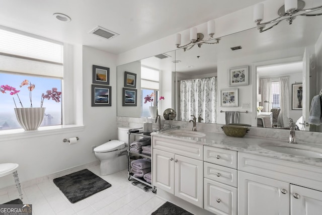 bathroom with toilet, double vanity, a sink, and visible vents