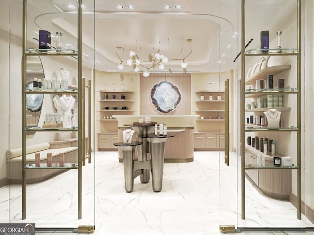 wine room with marble finish floor, built in features, and a raised ceiling