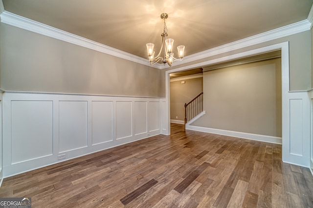 empty room with an inviting chandelier, crown molding, and hardwood / wood-style floors