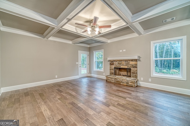 unfurnished living room featuring a stone fireplace, hardwood / wood-style flooring, coffered ceiling, and ceiling fan