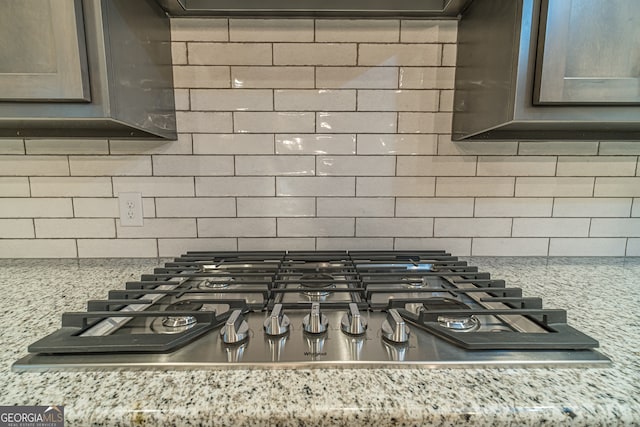 details featuring decorative backsplash, light stone counters, and stainless steel gas cooktop